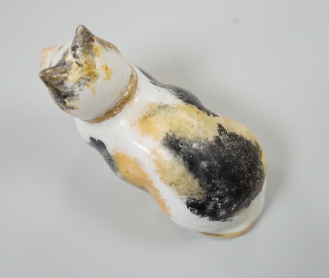 A rare small Staffordshire porcelain figure of a recumbent cat, c.1830-50. 6cm long, Cf. Dennis G.Rice Cats in English porcelain, colour plate 54., Provenance: Dennis G.Rice collection